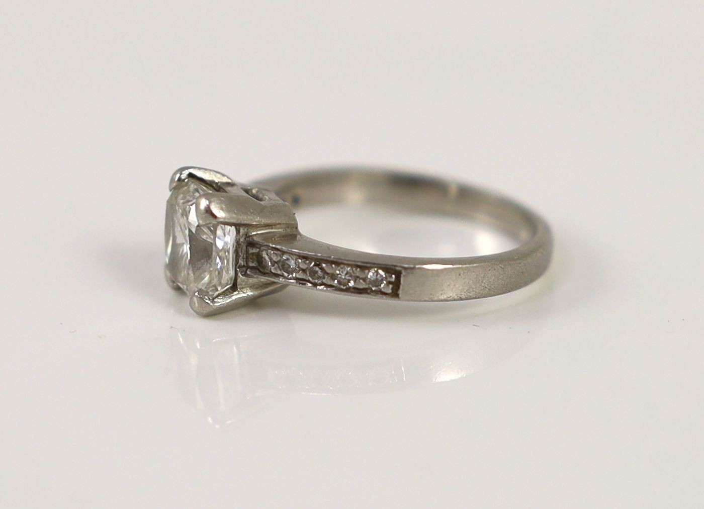 A modern platinum and single stone brilliant cushion cut diamond, with diamond set shoulders